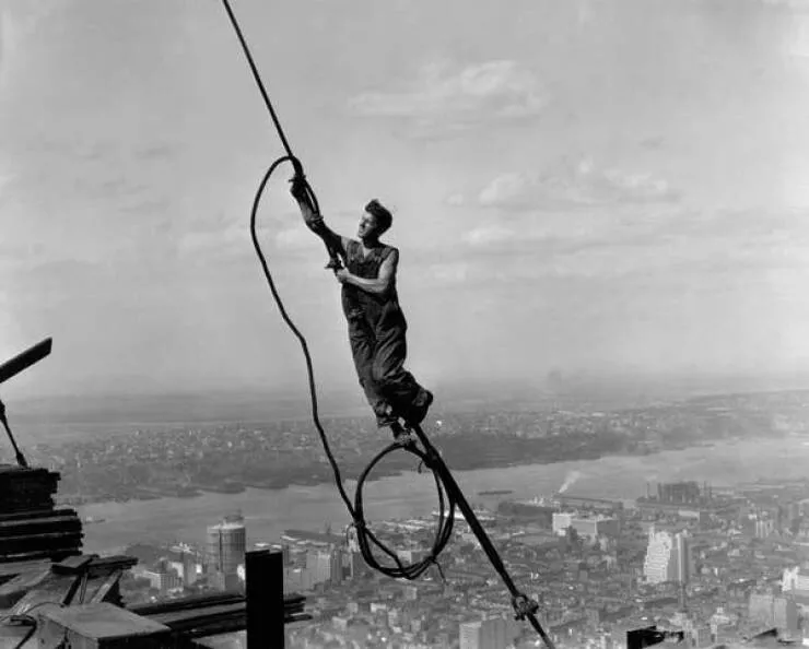 Intriguing images of historical construction projects - #11 A steelworker hanging effortlessly during the Empire State Building's construction.