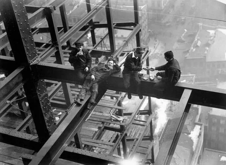Intriguing images of historical construction projects - #22 The photo depicts ironworkers enjoying lunch on a girder twenty stories high, seemingly unbothered by the drop below.