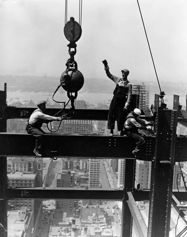 Intriguing images of historical construction projects - #23 Members of a derrick gang are fixing a beam during the Empire State Building's construction, with the bustling streets of New York far beneath them.