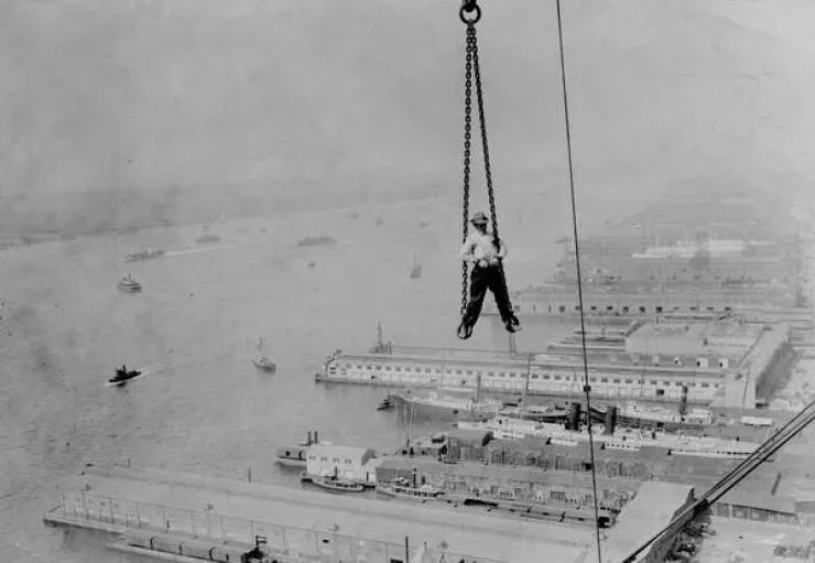 Intriguing images of historical construction projects - #3 A worker is hoisted up to a 30-story skyscraper on New York's waterfront.